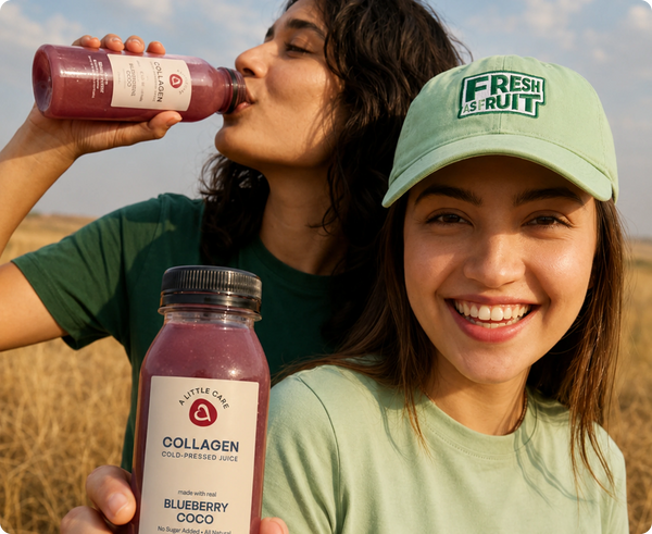 Two women outdoors in a field, one drinking from a bottle of A Little Care Collagen Cold-Pressed Juice and the other holding the same bottle. The woman in front wears a light green cap with 'FRESH IS FRUIT' and a light green T-shirt.